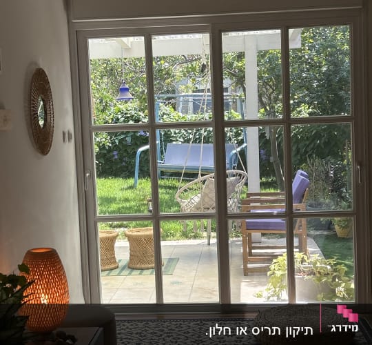 חלון זכוכית עם נוף לגינה ירוקה וריהוט גן